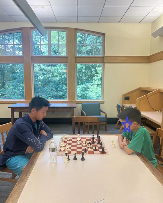 A volunteer and a learner practicing chess across a table
