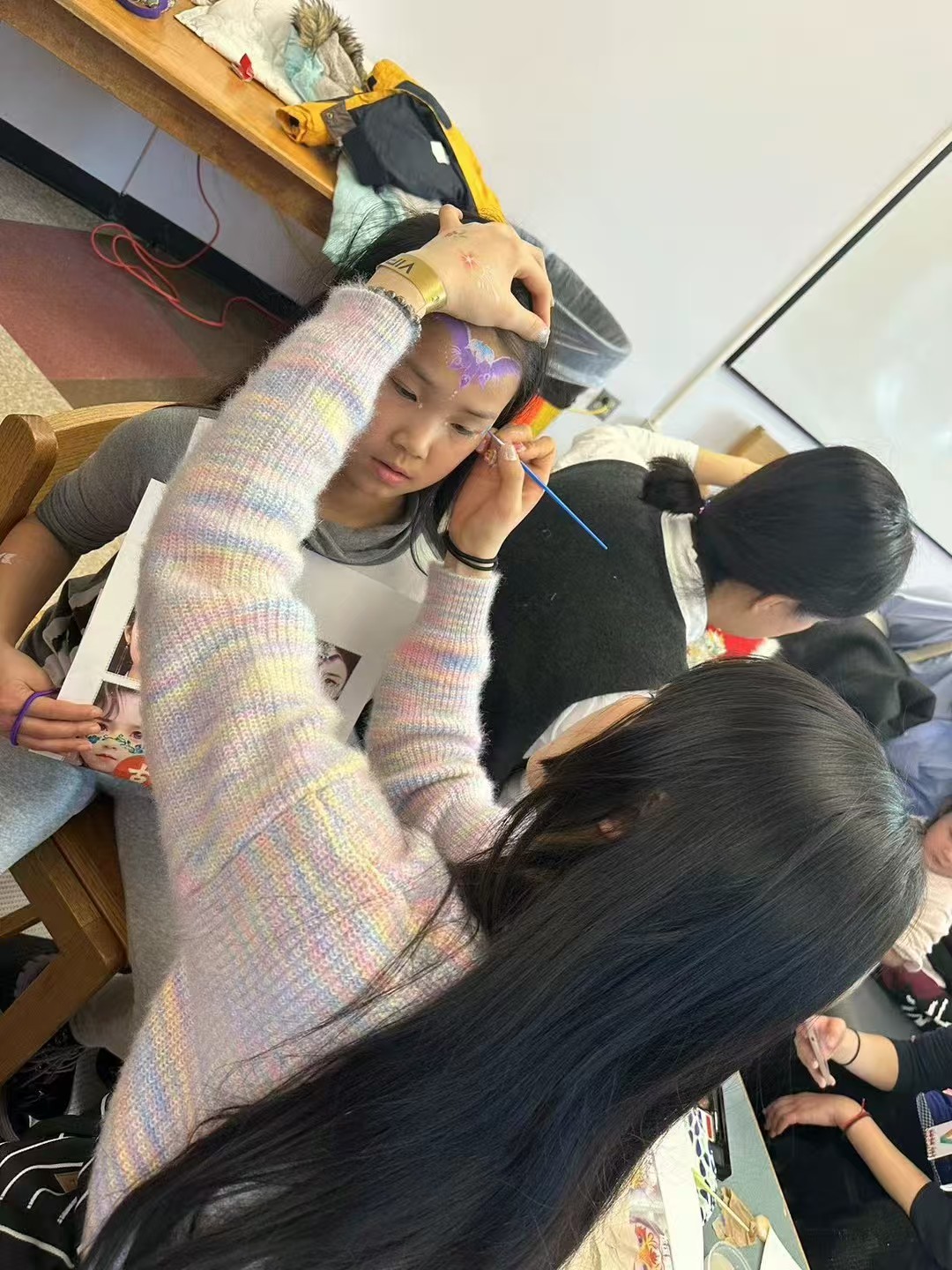 A volunteer painting a butterfly design on a child’s forehead