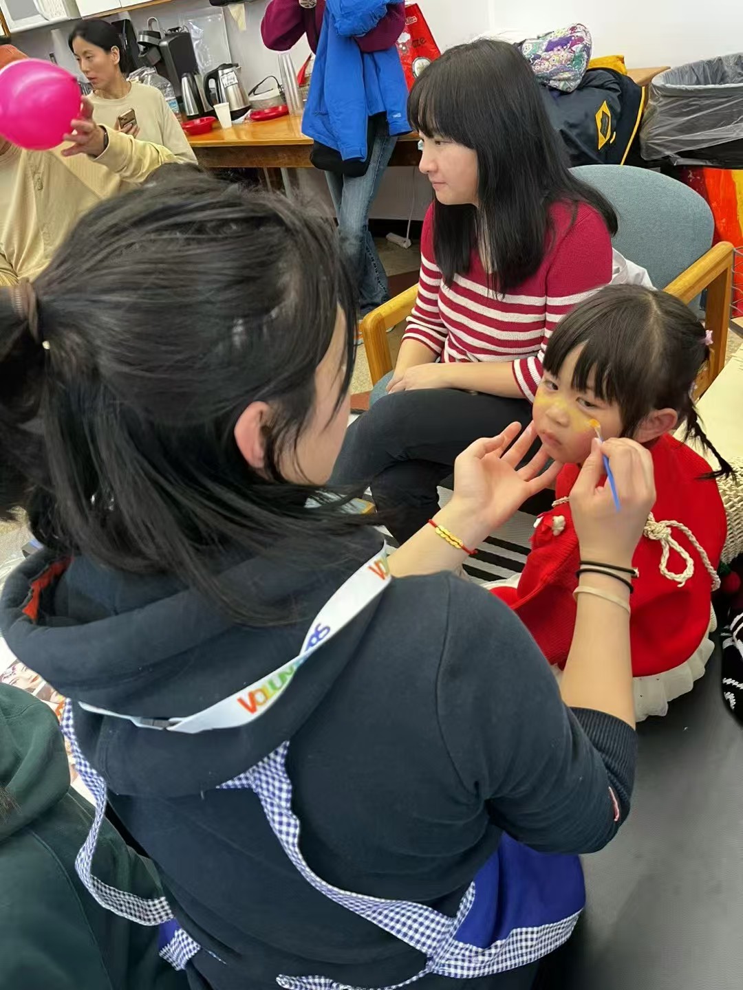 A volunteer painting a yellow design on a child’s face