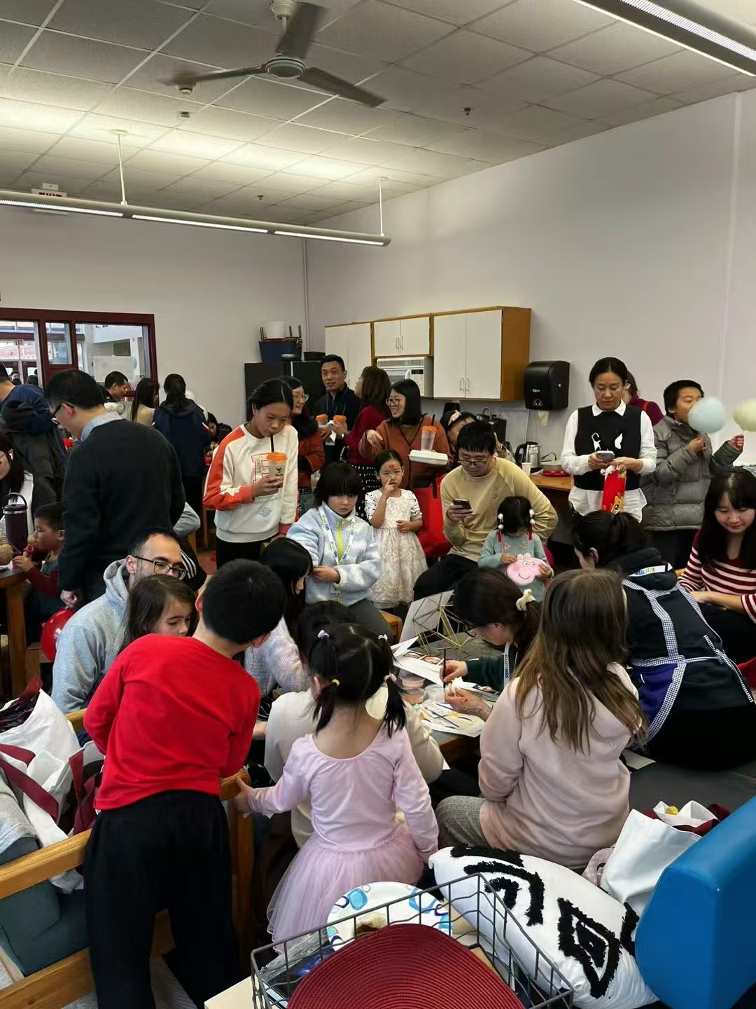 Children, families, and volunteers gathered around face painting activities