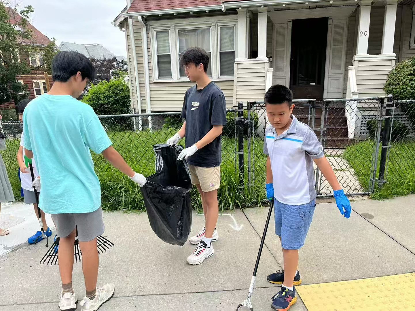 Volunteers with gloves, litter pickers, and a trash bag during a street cleanup